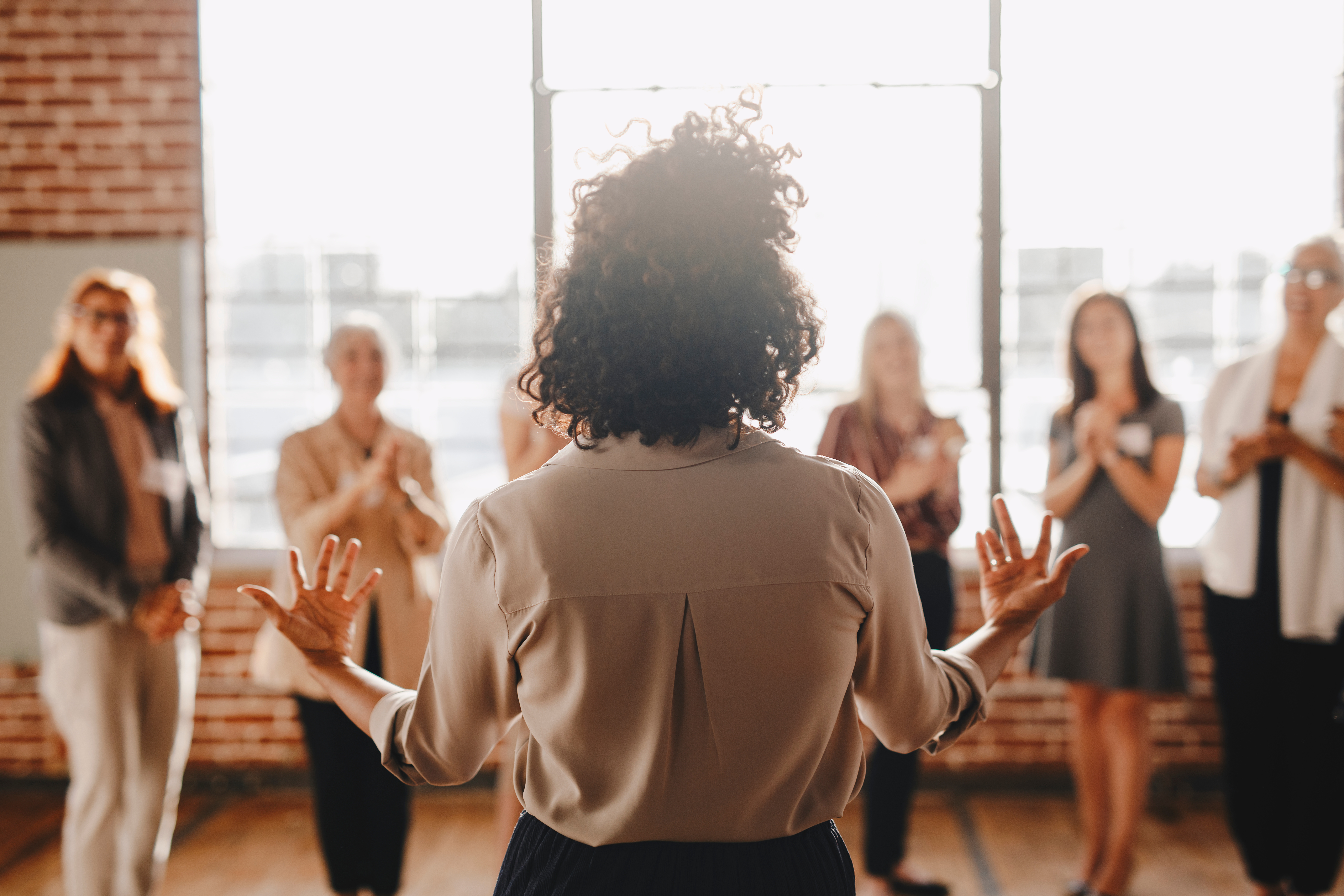 The back view of a person standing before a group and gesturing